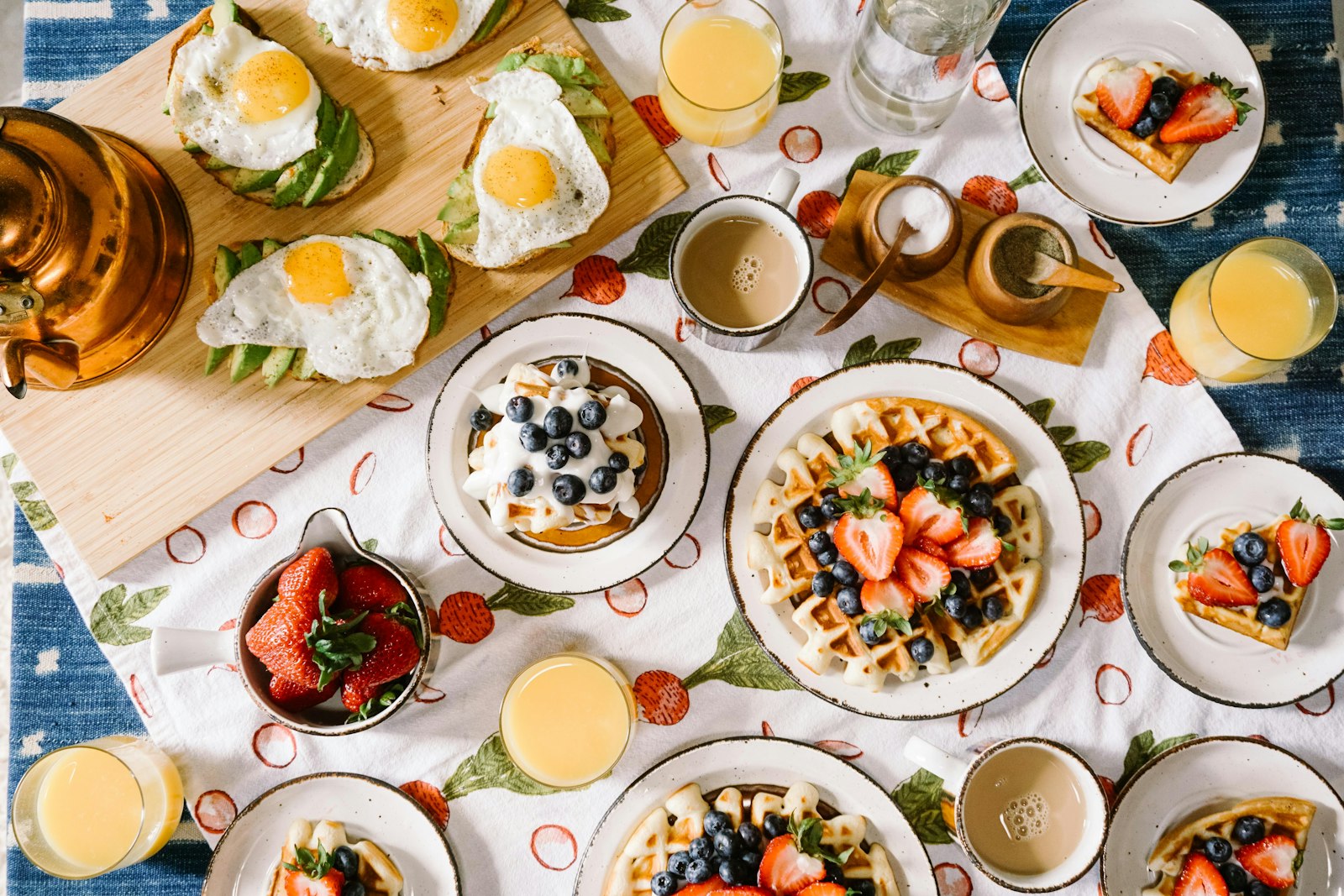 A generous breakfast spread of eggs, waffles, fruit and coffee laid out on a table
