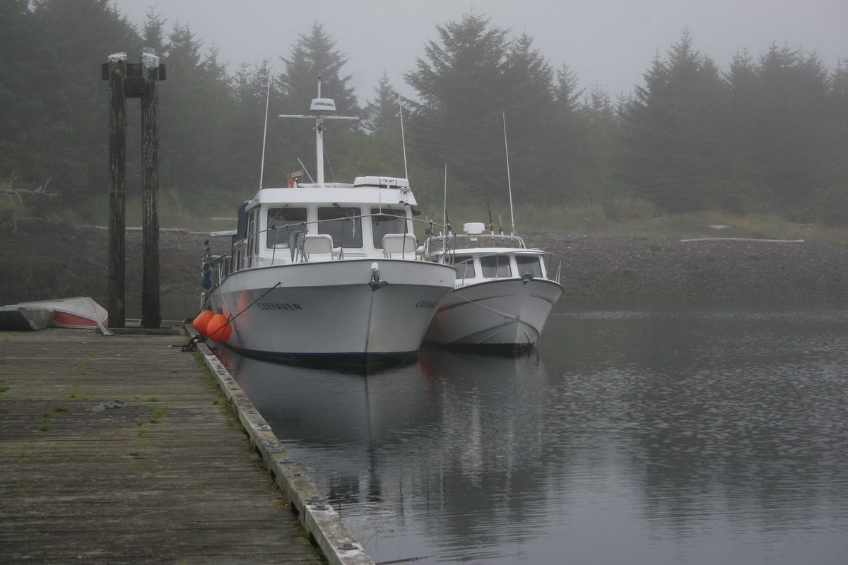 Fishing boats moored at a misty Haida Gwaii dock in the morning